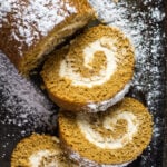 Overhead shot of gingerbread cake roll with slices cut out on a baking tray.