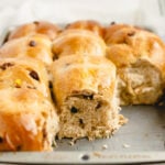The baking tray with soft, fluffy buns, three pieces torn away to reveal the airy crumb inside, with chocolate chips studded throughout.