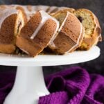 A glazed peanut butter and jam bundt cake with three slices cut out overlapped on a white cake stand.