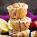 A stack of three strawberry lemon muffins drizzled with a glaze on baking tray.