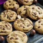 Overhead shot of chocolate chip cookies with Maltesers on a baking tray.