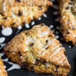 Overhead shot of chocolate chip scones drizzled with a glaze on a baking tray.