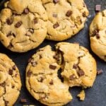 Overhead shot of chocolate chip peanut butter cookies on baking tray with one cookie broke in half to show peanut butter filling.