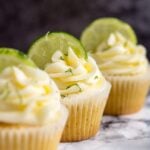 A row of three frosted Margarita cupcakes with lime slices.