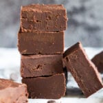 A stack of four pieces of chocolate fudge with one piece leaning up against it.