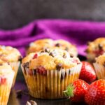 Strawberry chocolate chip muffins on a baking tray with strawberries.