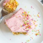 A slice of frosted funfetti sheet cake served on a small white plate with a fork.