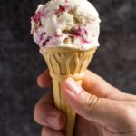 A scoop of no-churn raspberry ripple ice cream on a wafer cone.