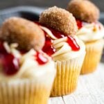 A sideview of a row of three frosted Jam Doughnut Cupcakes.