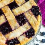 Overhead shot of a homemade blueberry pie in a glass pie dish.
