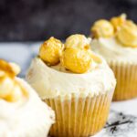 A row of three frosted toffee popcorn cupcakes.