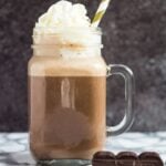 A mason jar filled with chocolate eggnog and whipped cream on top.