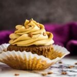 A frosted gingerbread cupcake with the wrapper peeled off.