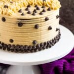 Mocha layer cake on a white cake stand.