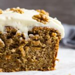 A close-up shot of half a Carrot Cake Loaf topped with a thick layer of cream cheese frosting.