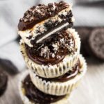 An overhead shot of a stack of Mini Oreo Cheesecakes with the top cheesecake cut in half to show whole Oreo crust.
