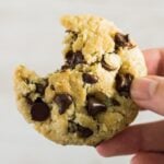 A bitten Coconut Chocolate Chip Cookie being held up by hand.