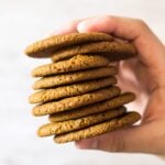 A stack of Homemade Gingernut Cookies being held up by hand.