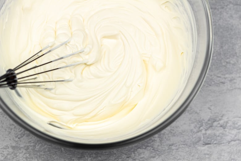 Whipping double cream to stiff peaks in mixing bowl.